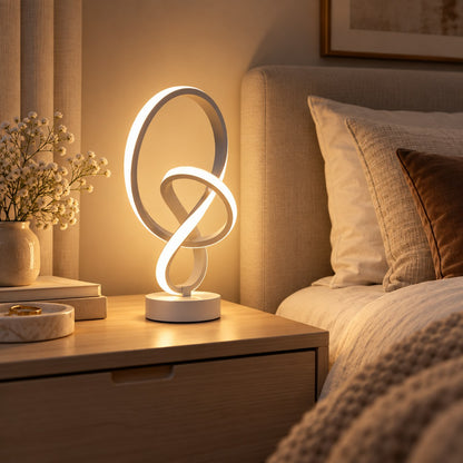 Lampe à poser LED design blanche allumée sur une table de chevet
